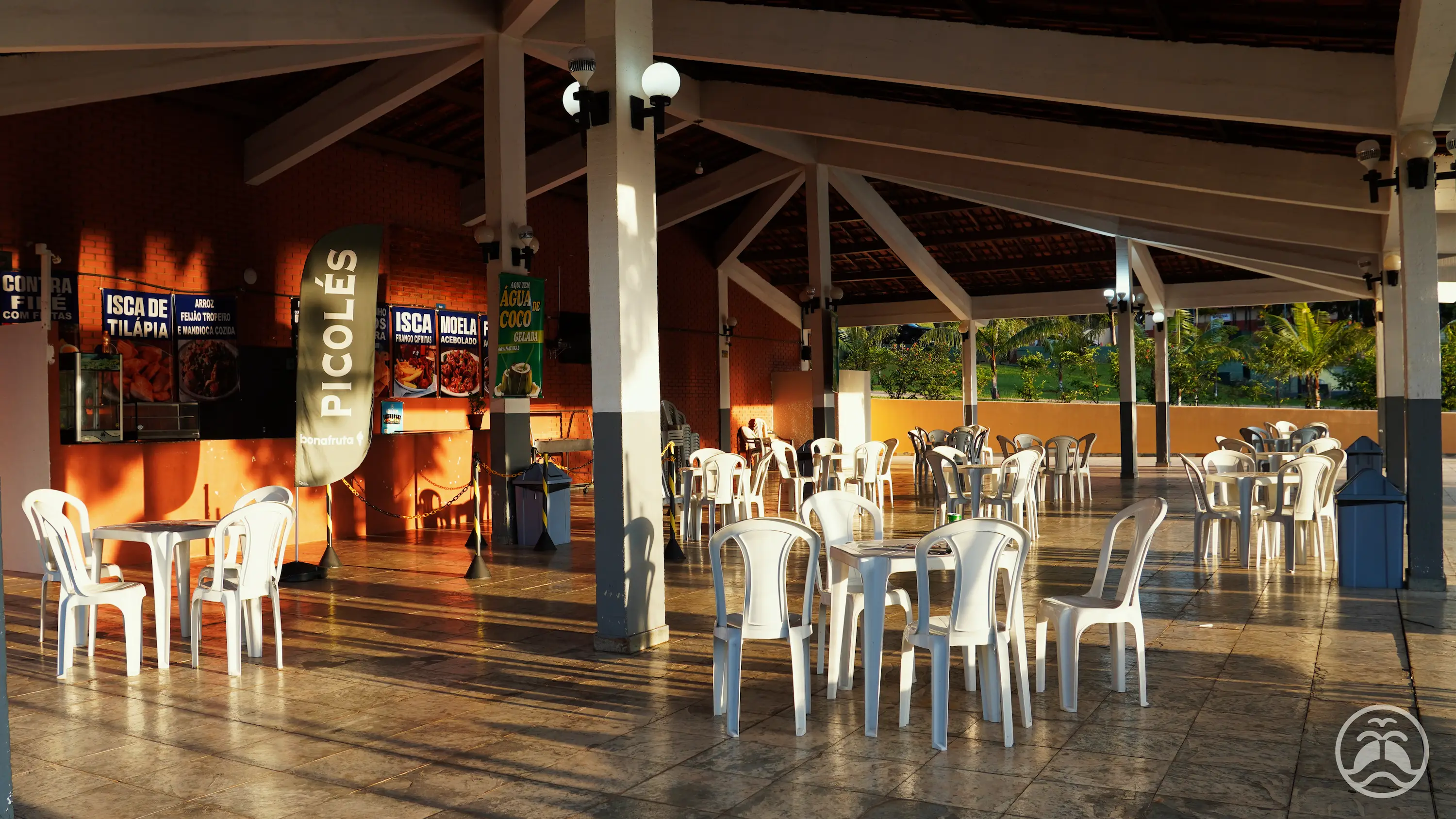 Ambiente interno do restaurante com mesas, cadeiras e balcão de atendimento