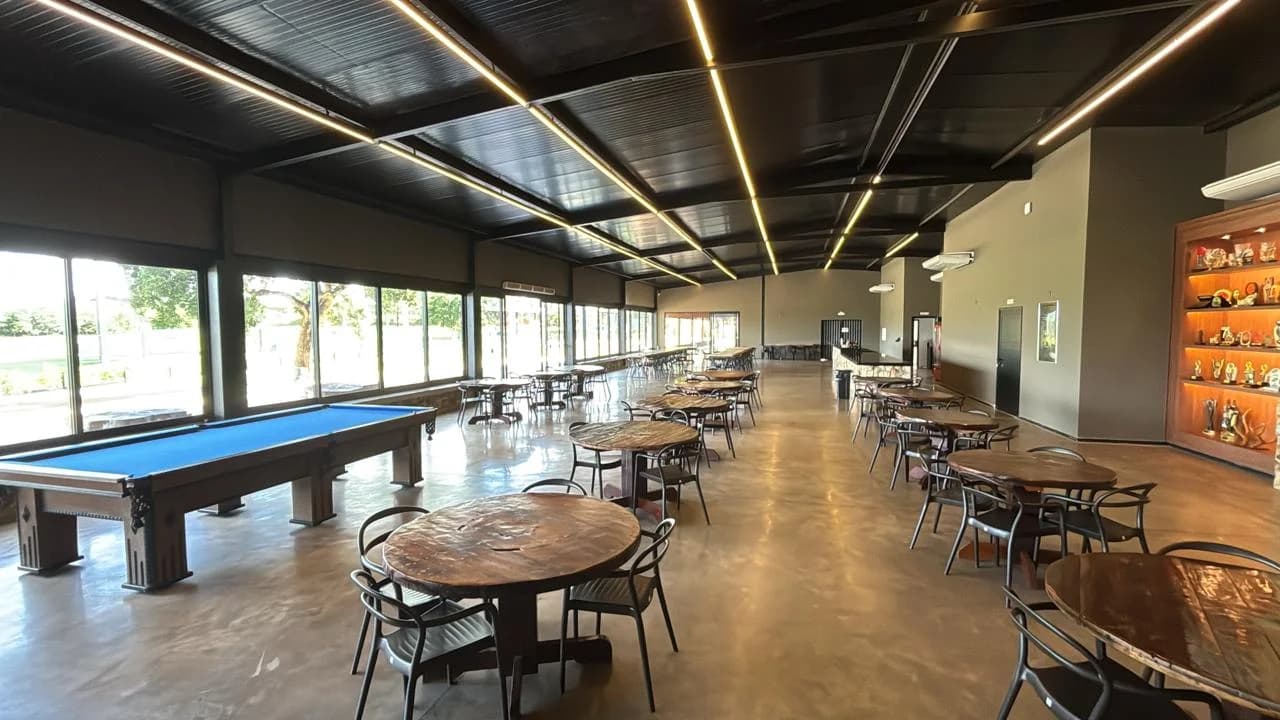Salão do Clube de Tiro de Uberlândia com mesas e mesa de sinuca